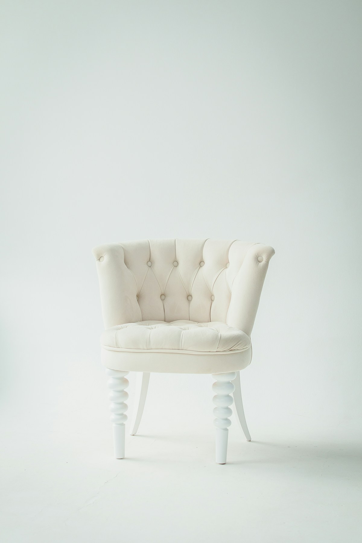 A well-kept cream upholstered chair against a quiet, pale wall